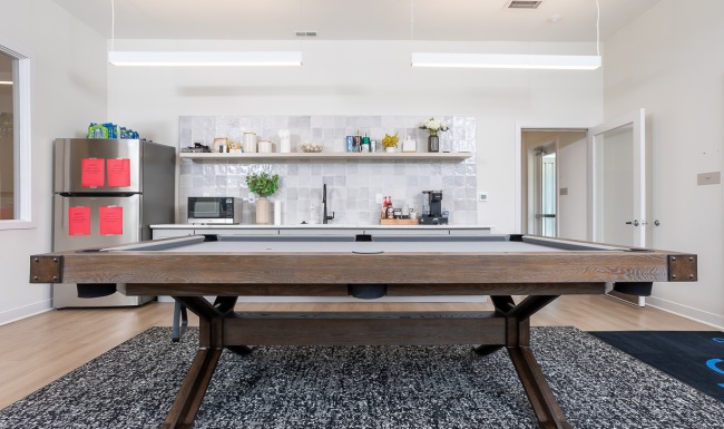 Pool table and galley kitchen with styled shelves