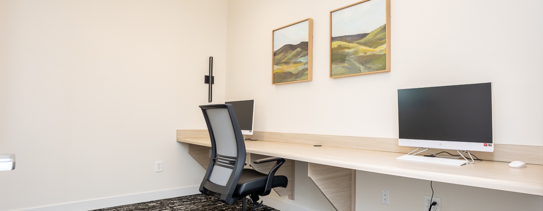 Room with long desk, chairs, and Apple computers