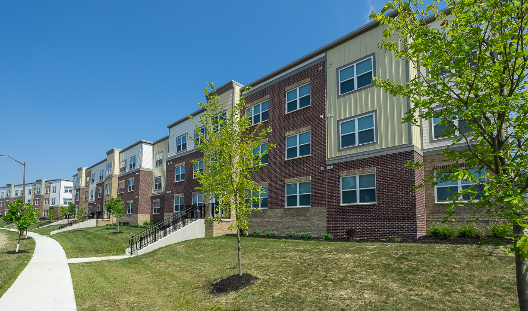 Apartment building exterior with trees and sidewalk