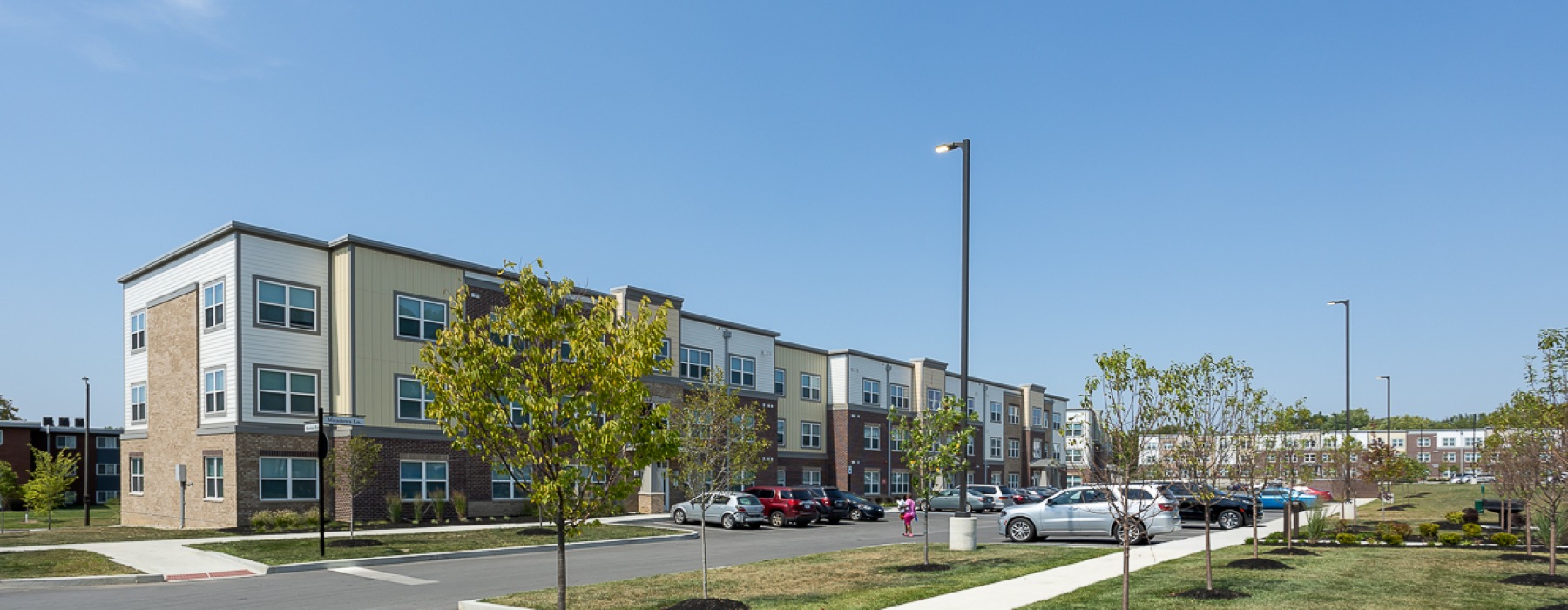 Apartment building exterior with trees and cars parked