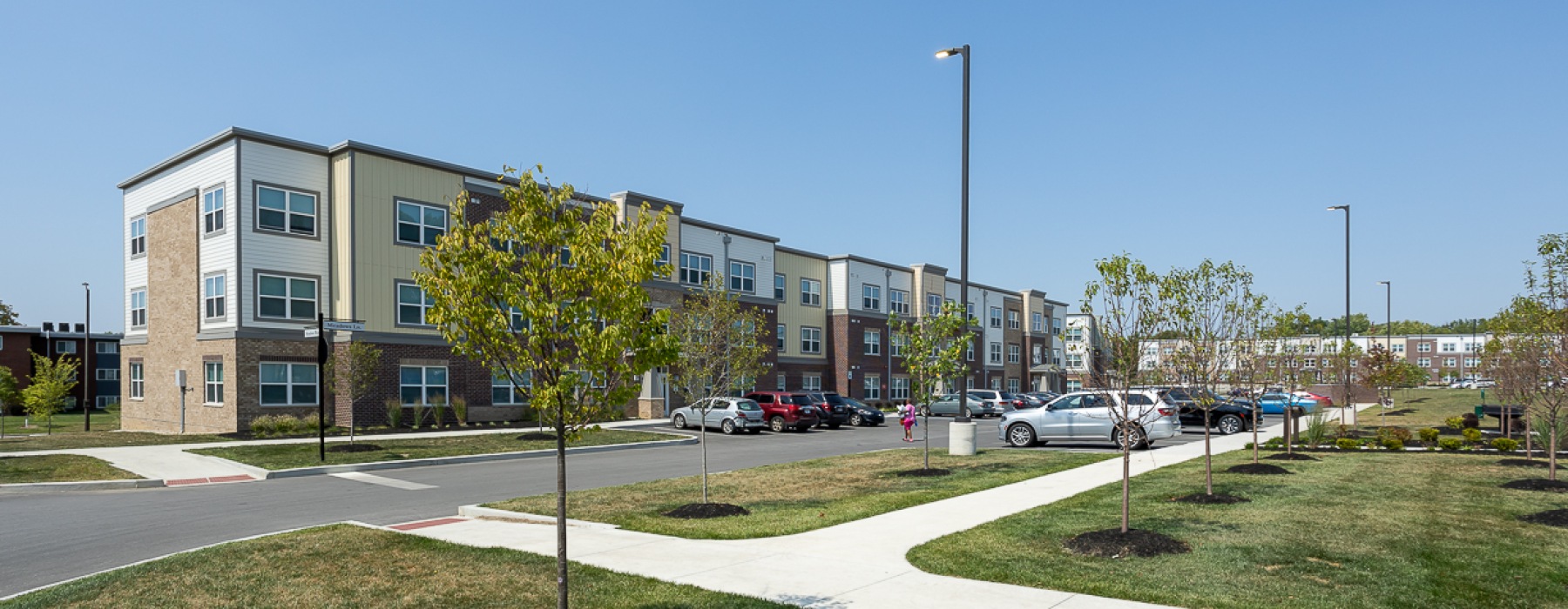 Apartment building exterior with trees and cars parked